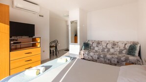 Ein Hotelzimmer mit Bett, Fernseher auf einem Holzschrank, Schreibtisch mit Stuhl und Spiegel an der Wand.