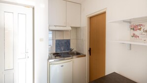 Eine kleine Küche mit weißen Schränken, einer kompakten Arbeitsfläche und einem eingebauten Backofen.