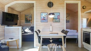 Ein gemütliches Blockhaus-Interieur mit Essbereich, einer Couch, einem Fernseher und einer Küchenzeile.