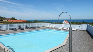 En swimmingpool med solstolar och utsikt över havet.