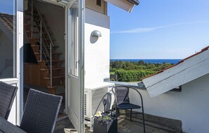 Enjoy the serene sea views from this balcony, featuring a comfortable seating area with a table and vase of flowers.