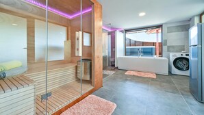 A modern bathroom with a glass enclosure, a bathtub, a washing machine, and a toilet. - Nice home in Ljubescica with sauna (Ljubescica)