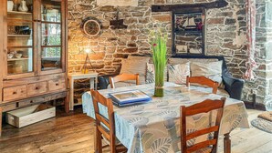 A rustic dining area with a wooden table set for four, surrounded by stone walls and a wooden cabinet. - 2 bedroom beach front home in Cherrueix (Cherrueix)
