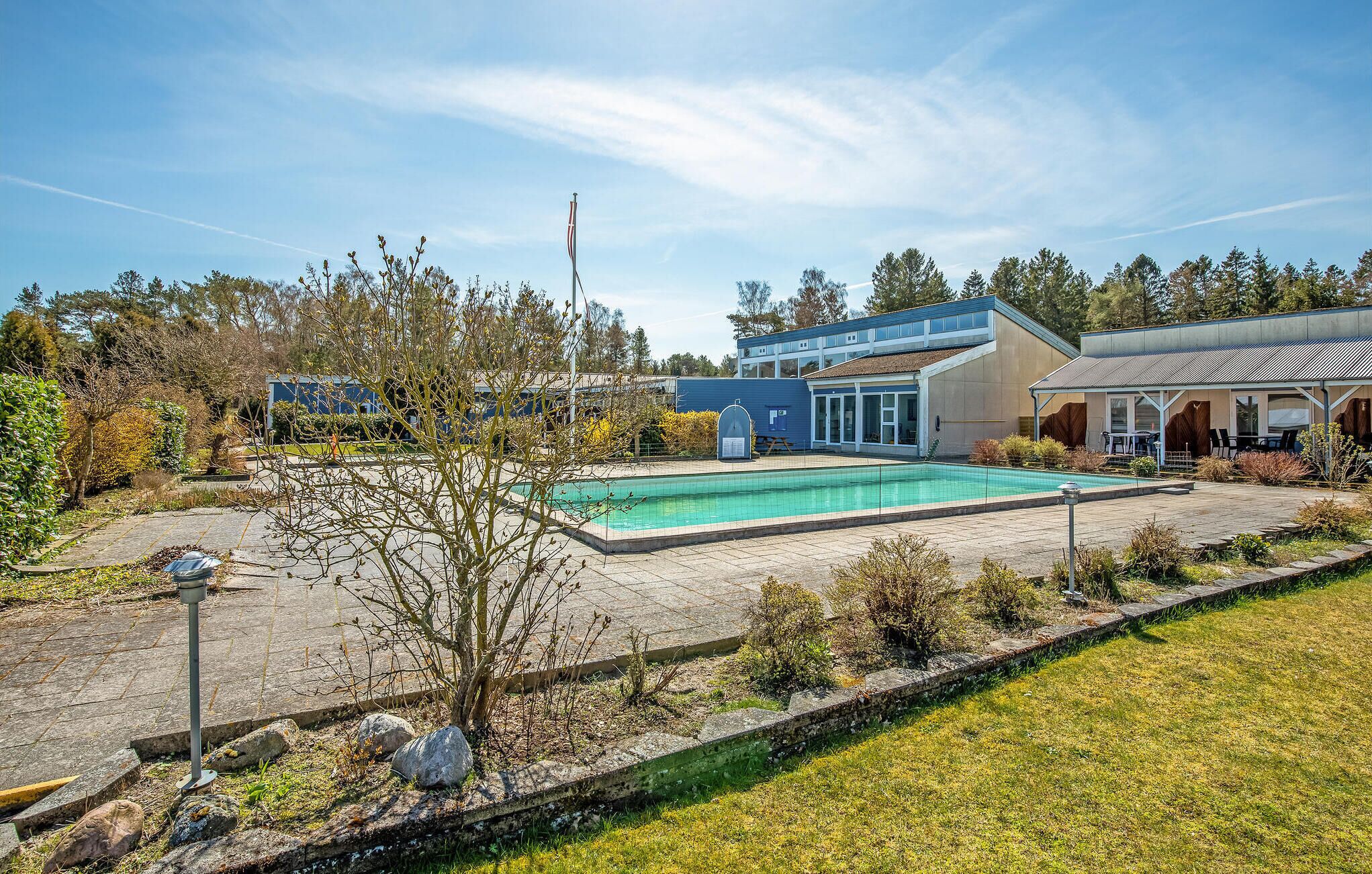 Ein Wohnhaus mit Schwimmbad, einer überdachten Terrasse und einem großen Gebäude mit blauer Fassade.