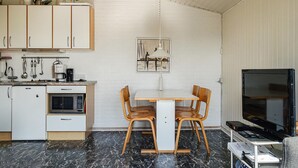 Een kleine keuken met een eethoek, een televisie en een magnetron.
