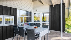 An outdoor dining area with a table and chairs, large windows, and a view of greenery. - Stunning home in Sydals with sauna (Sydals)