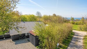 A small, single-story building with a tiled roof, surrounded by greenery and a gravel driveway. - Stunning home in Sydals with sauna (Sydals)