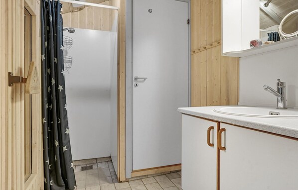 Une salle de bain avec une douche, un lavabo et des meubles en bois.