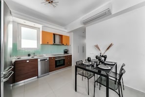 Une cuisine moderne avec un coin repas. Elle comprend un lave-vaisselle, un four et une table dressée pour le repas.