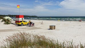 A beach scene with a lifeguard station, a yellow truck, and a flag.