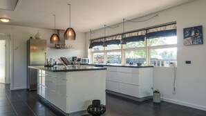 A modern kitchen with a central island, pendant lighting, and large windows.