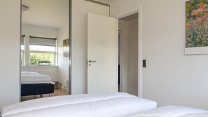 A bedroom with a bed, a wardrobe, and a door leading to another room.