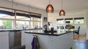 A modern kitchen with a central island, stainless steel appliances, and pendant lighting.