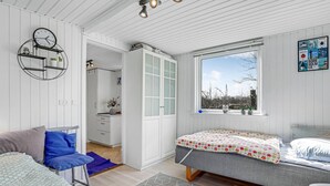 Un dormitorio con cama, una silla, un escritorio y una ventana con vista a árboles.