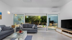 A modern living room with a grey sofa, a glass coffee table, and a flat-screen TV. - Stunning home in Zestilac (Zestilac)