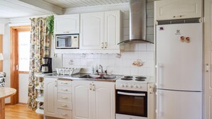 Une cuisine avec des meubles blancs, une cuisinière, un four à micro-ondes et un réfrigérateur.