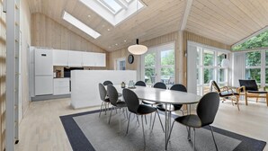Une cuisine moderne avec des meubles blancs, un îlot central et un coin repas comprenant une table ronde et des chaises.