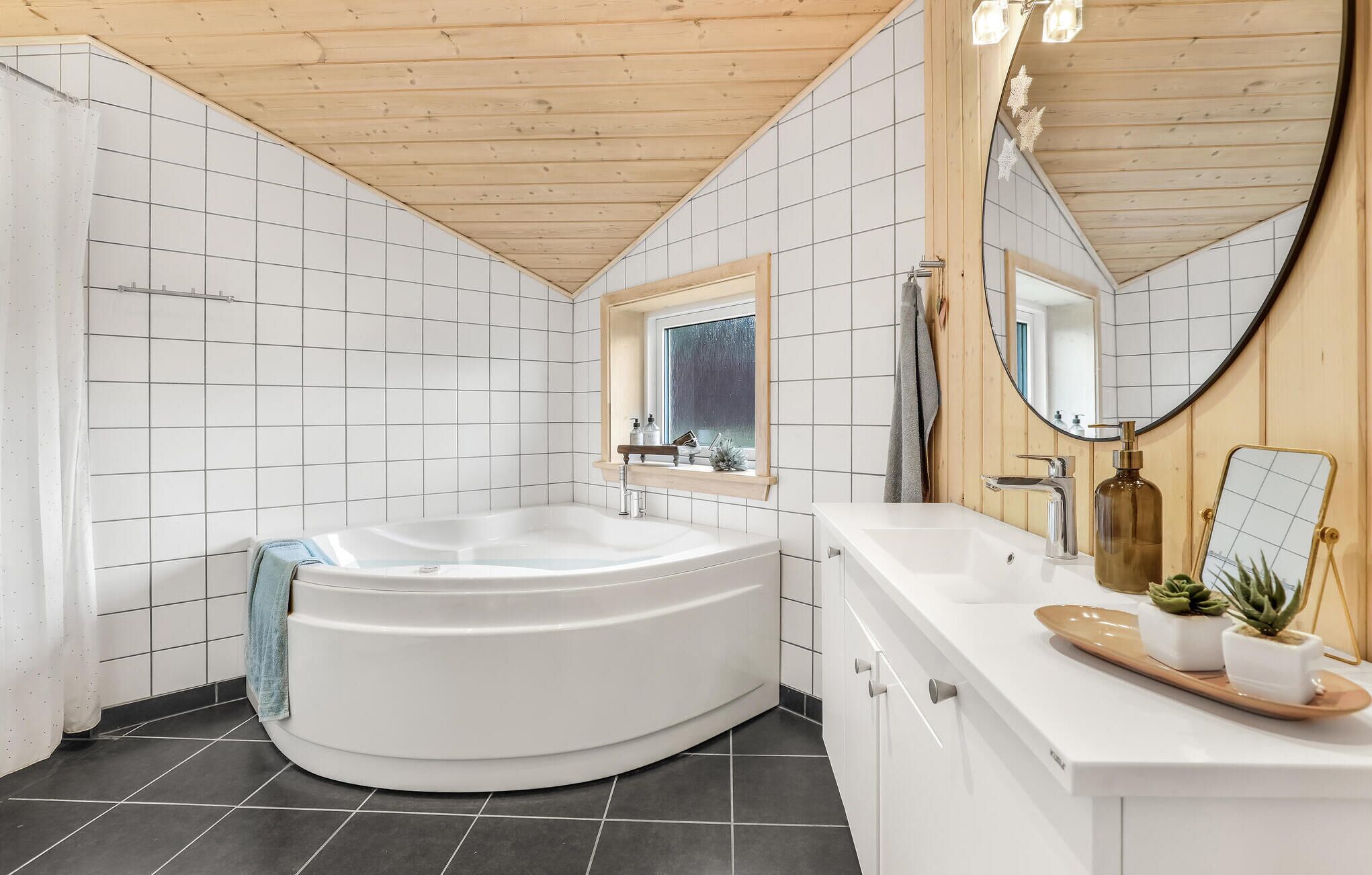 Une salle de bain moderne avec une baignoire sur pieds, un meuble-lavabo avec un miroir et une fenêtre au-dessus du lavabo.