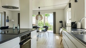 A modern kitchen with a central island, a dining area with chairs, and a view to the outside. - 2 bedroom cozy home in Svaneke (Svaneke)