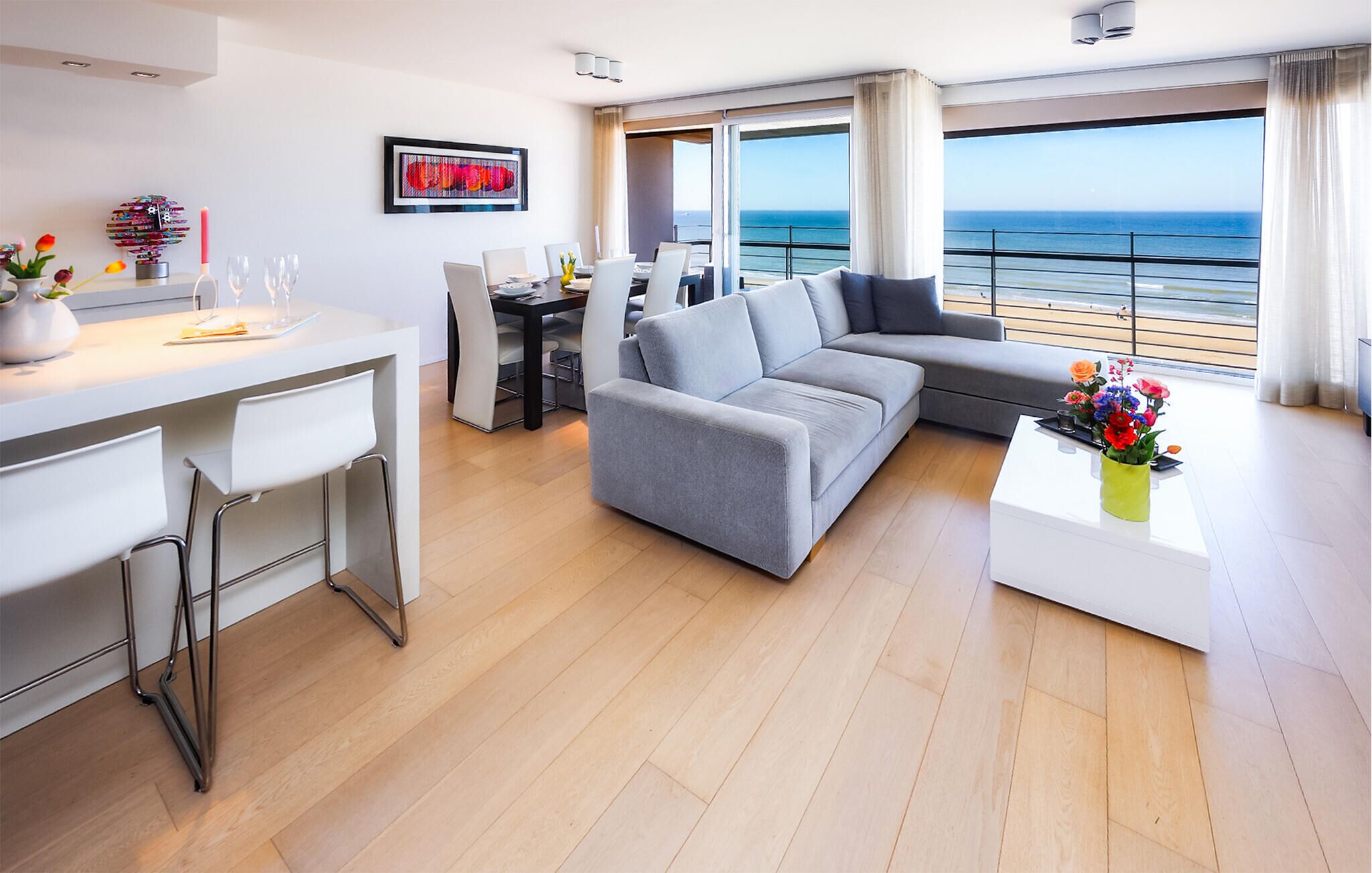 Un salon moderne avec un canapé, une table à manger et une vue sur l’océan.