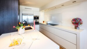 A modern kitchen with white cabinetry, a stainless steel refrigerator, and a toaster on the counter. - Res. Vent de Sable ref.: 115 (Oostende)
