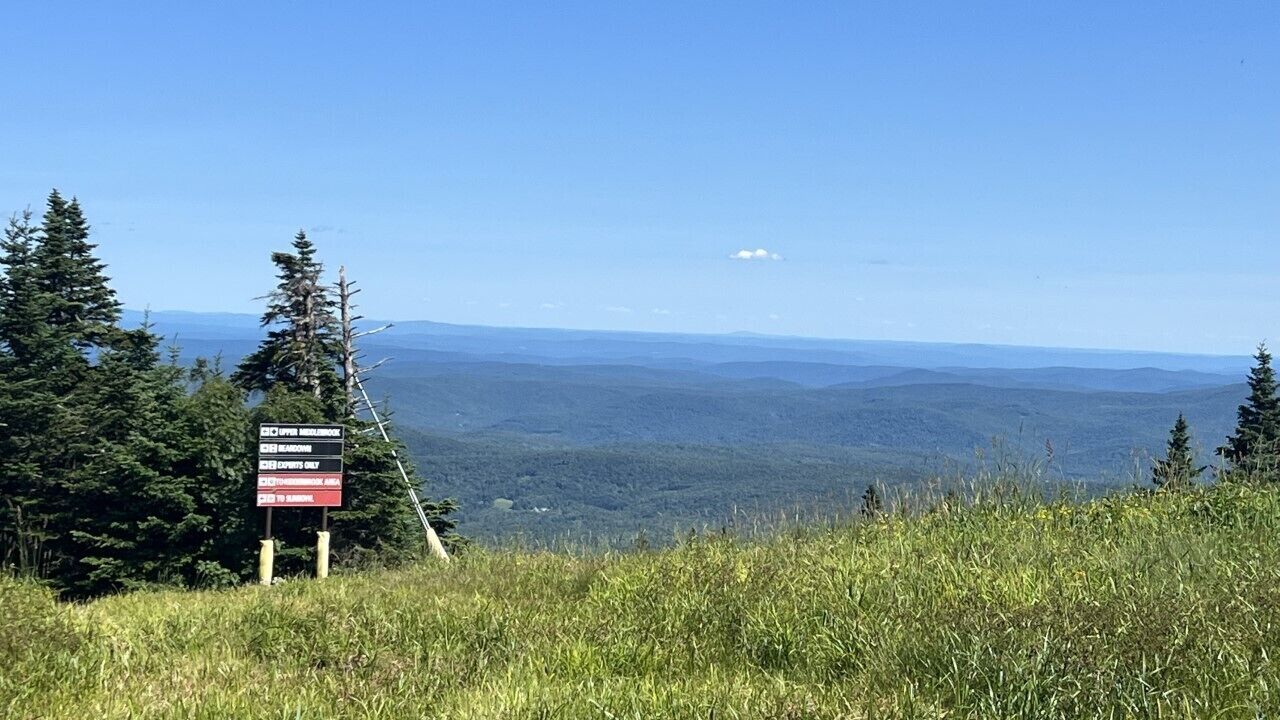 A signpost with a view of a mountainous landscape.