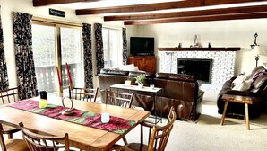 A cozy living room with a wooden dining table, leather sofa, and a fireplace. - MINUTES TO STRATTON AND BROMLEY! (bondville)