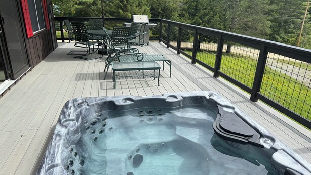 A hot tub on a wooden deck with outdoor furniture and a grill. - MINUTES TO STRATTON AND BROMLEY! (bondville)