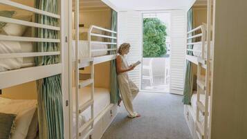 Ein Zimmer mit Etagenbetten, eine Person liest, und es bietet Blick auf Grün.