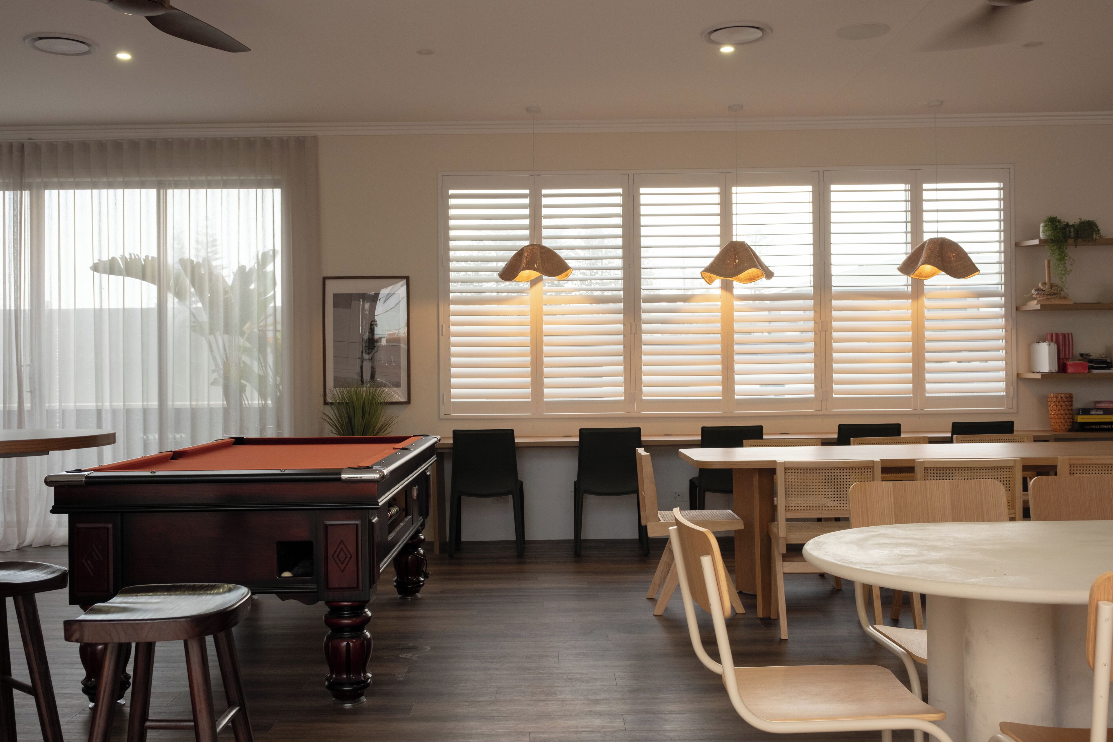 Une table de billard avec des chaises, une table à manger avec des chaises et un coin bar avec des tabourets.