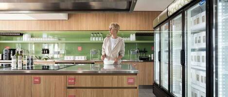 Una cocina moderna con una isla central, un refrigerador con puertas de vidrio y cajones etiquetados para ollas, cubiertos y platos.