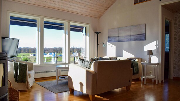 A spacious living room with a large window, a flat-screen TV, and a comfortable sofa. - Amazing home in Rockneby with sauna (Rockneby)