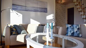 A modern living room with a round glass coffee table, a beige sofa with patterned cushions, and a painting on the wall. - Amazing home in Rockneby with sauna (Rockneby)