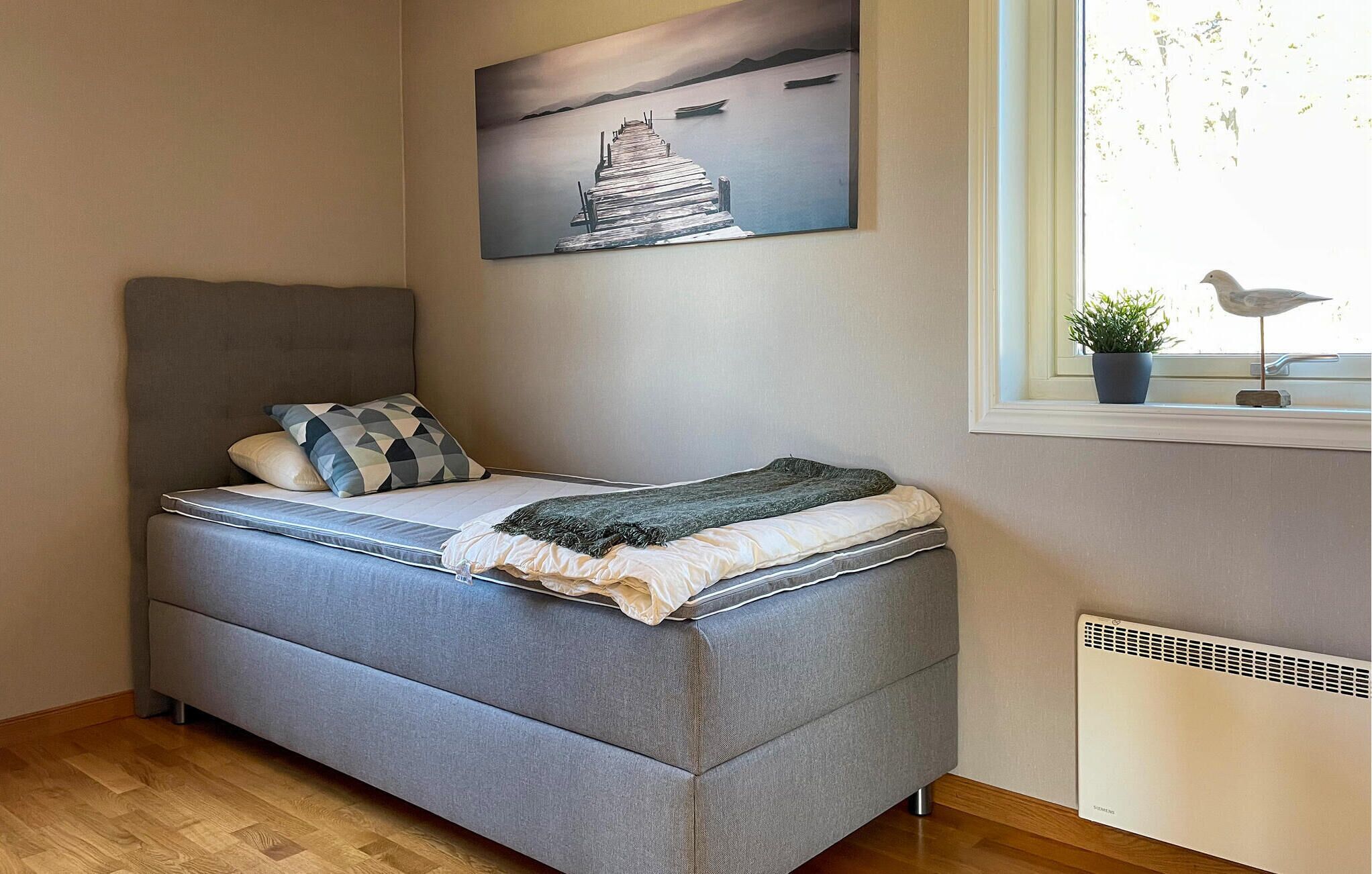 Een netjes ingerichte slaapkamer met een bed, kussens, een raam met uitzicht en een radiator.