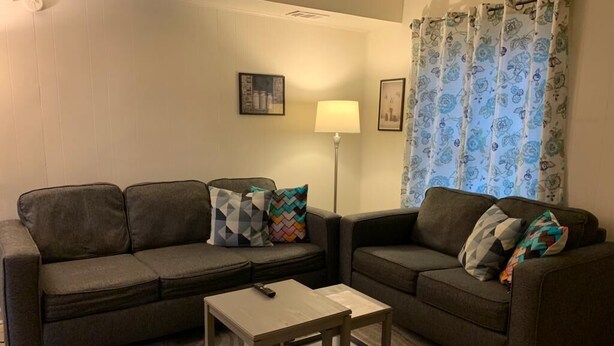 Een woonkamer met twee banken, een salontafel en een lamp.