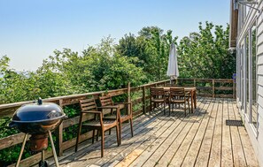 Enjoy al fresco dining on this deck with a barbecue grill, surrounded by lush greenery and trees.