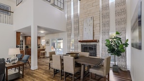 A spacious living area with a high ceiling, wooden flooring, and a dining table set with chairs. - North Austin Oasis near Domain  20 min to Downtown (Austin)