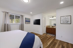 A bedroom with a bed, a TV, a bathroom with a sink and mirror, and a window with curtains. - North Austin Oasis near Domain  20 min to Downtown (Austin)