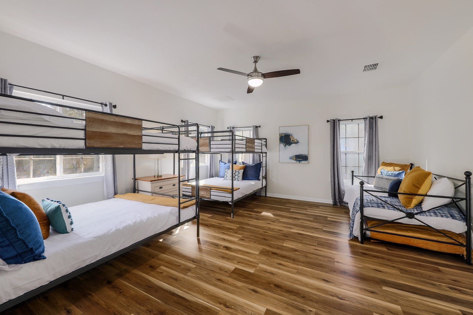 A dormitory room with bunk beds, a ceiling fan, and a window with curtains.