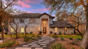 A stone house with a central entrance, surrounded by a garden with a stone pathway leading to the door. - North Austin Oasis near Domain  20 min to Downtown (Austin)