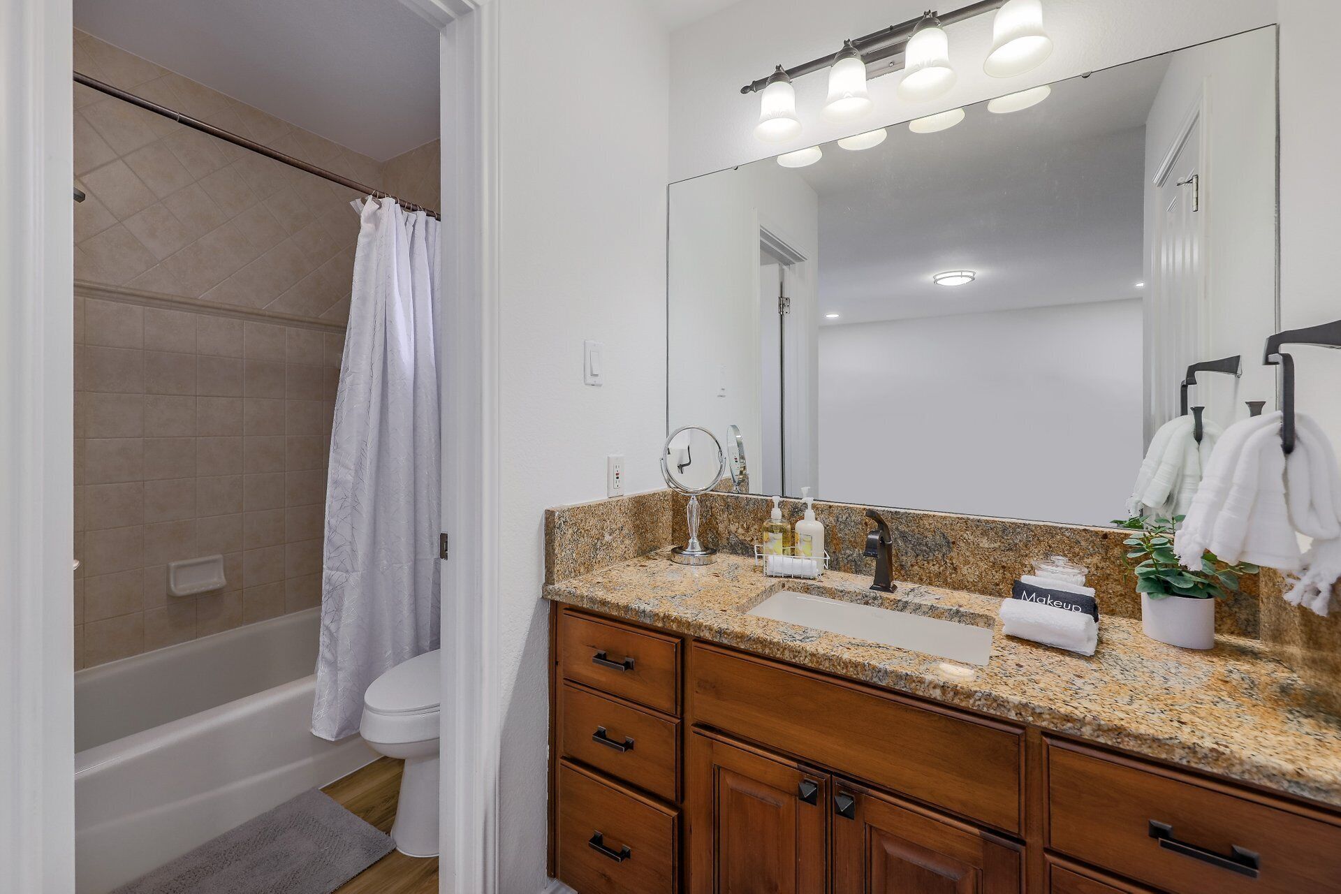 A bathroom with a shower, toilet, vanity with a mirror, and a sink.