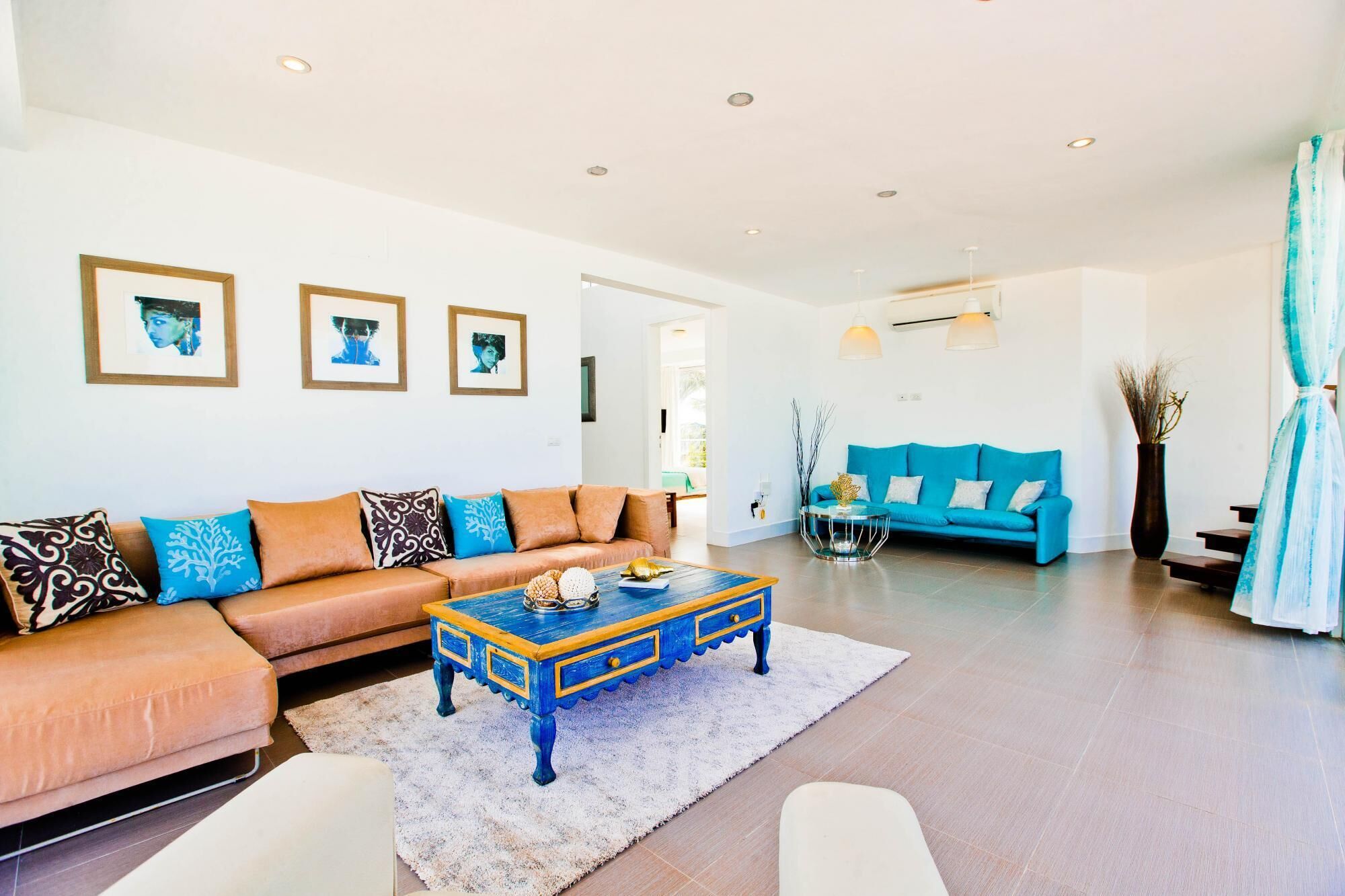 A spacious living room with a blue sofa, a wooden coffee table, and a large window.