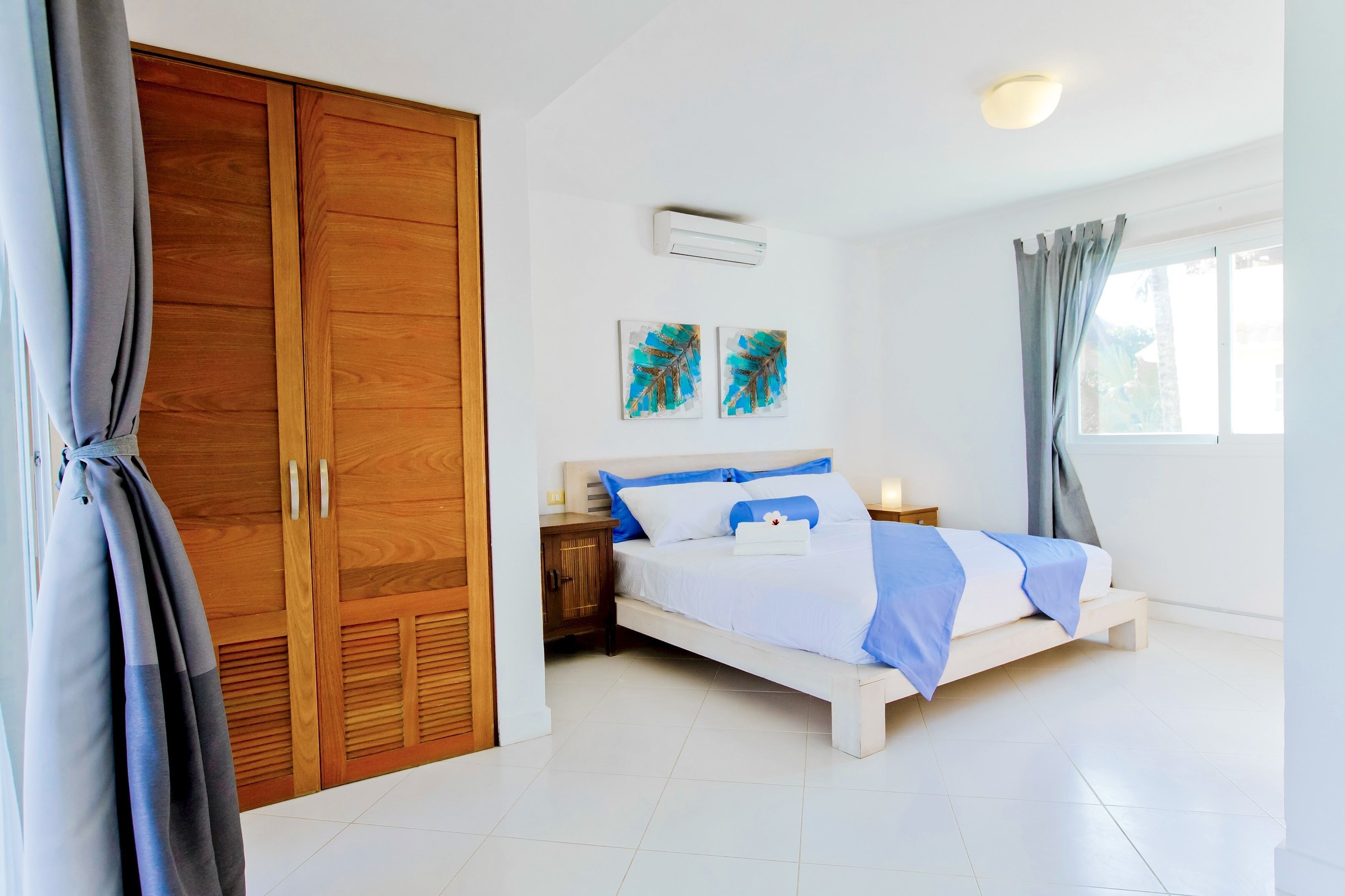 Une chambre à coucher comprenant un lit, une armoire en bois et deux unités de climatisation fixées au mur.