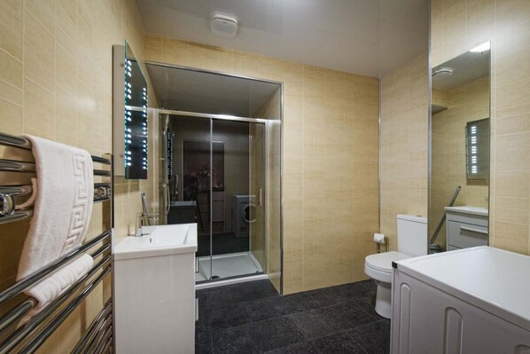 A modern bathroom with a glass shower enclosure, a toilet, and a sink.
