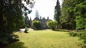 Un grand bâtiment historique doté d’une pelouse bien entretenue et de grands arbres.