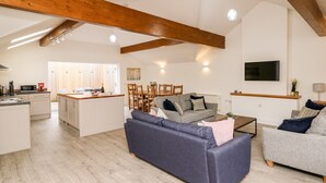 A spacious living area with a kitchen, dining table, and sofas. - Bridgend Cottages (Llandrindod Wells)