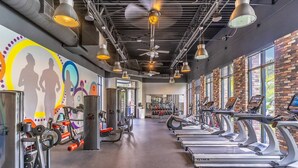 A gym with treadmills, weight machines, and a mural on the wall. - 314 Festival (Davenport)