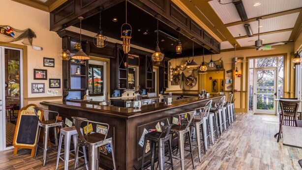 A bar area with a central counter, multiple stools, and hanging pendant lights. - 314 Festival (Davenport)
