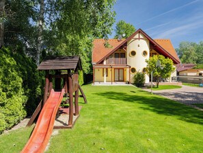 A house with a red roof, a wooden play structure with a slide, and a well-maintained lawn. - Apartment Jókai by Interhome (Balatonszarszo)