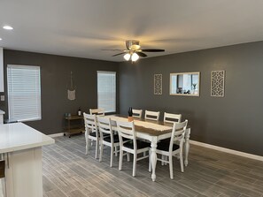 Uma sala de jantar com mesa, cadeiras, ventilador de teto e painéis decorativos na parede.